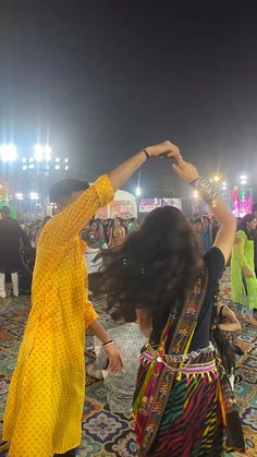 two women dancing in the middle of a carpet covered area at night with lights on