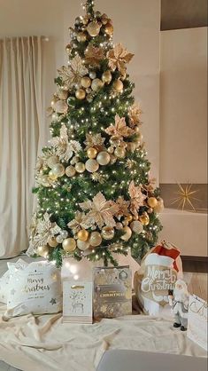 a christmas tree with gold ornaments and other items on the table in front of it