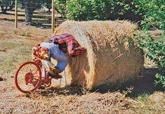 a person riding a bike next to a hay bale