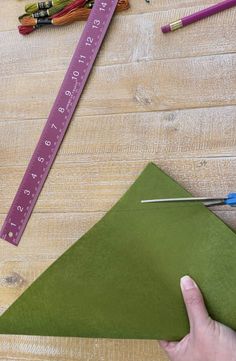 someone is making a triangle out of green paper and crayons on the table