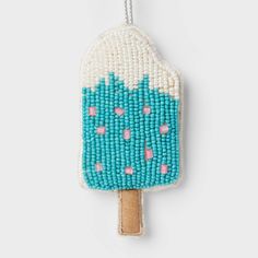 an ice cream popsicle beaded ornament hanging from a string on a white background