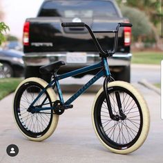 a blue bicycle parked on the sidewalk next to a black truck in front of a house