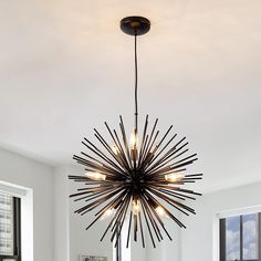 a modern chandelier hanging from the ceiling in a living room with white walls