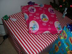 three wrapped presents sitting next to each other under a christmas tree with snowman and princesses on them