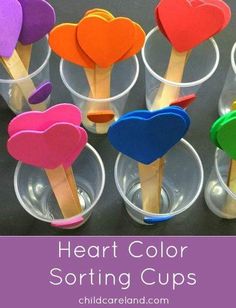 heart - shaped lollipops in plastic cups with wooden sticks