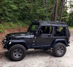 a black jeep is parked in the woods