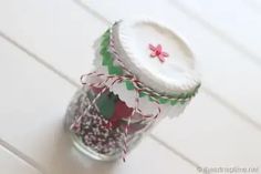 a jar filled with candy sitting on top of a white wooden floor next to a red ribbon