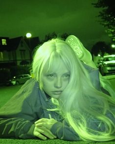 a woman laying on the ground with her hair blowing in the wind and green light