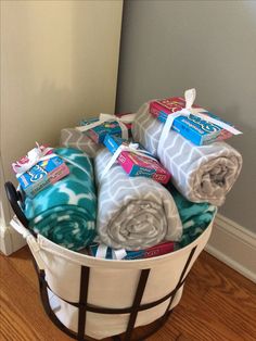 a basket filled with blankets sitting on top of a hard wood floor next to a wall