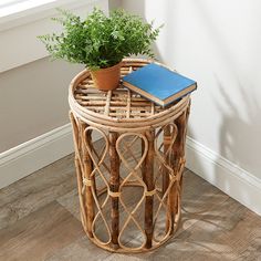 a plant sits on top of a wicker side table with a notebook in it