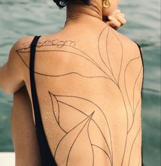 the back of a woman's body with tattoos on it