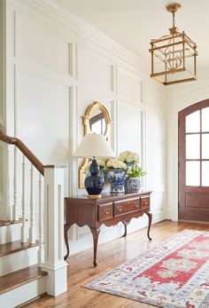 a room with a rug, table and mirror on the wall in front of it