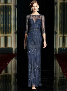 a model walks the runway in a blue gown with sheer sleeves and beading on it