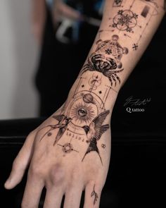 a person's hand with tattoos on it and an eye in the middle, surrounded by other symbols