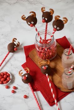 some candy sticks are in a glass with reindeer noses on them and other candies