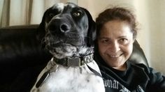 a woman sitting next to a black and white dog