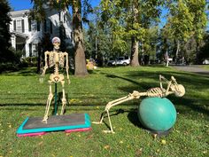 a skeleton sitting on top of an exercise mat in the grass next to a ball