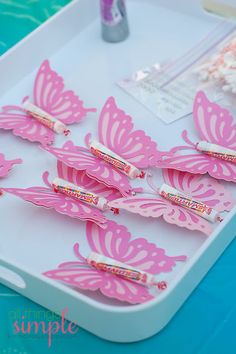 pink butterflies are sitting on a tray next to some toothbrushes and other items