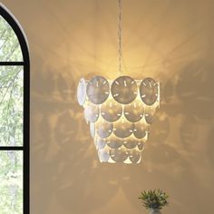 a chandelier hanging from the ceiling next to a vase with flowers in it