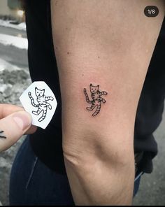 a person with a tattoo on their arm holding up a sticker that says cat