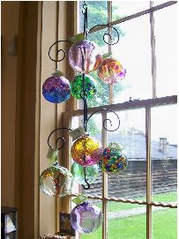 there are many colorful balls hanging from the window