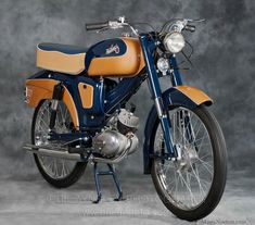 a blue and orange motorcycle parked on top of a cement floor next to a gray wall