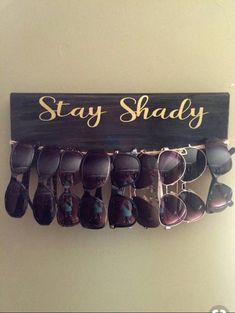 a wooden sign that says stay shady with sunglasses hanging from it's hooks on the wall