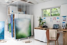 a desk with two laptops and paintings on the wall