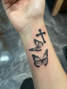 a woman's wrist tattoo with three butterflies and a cross on the left side