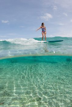 a woman riding a wave on top of a surfboard