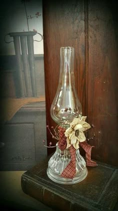 a glass vase sitting on top of a wooden table next to a red and white ribbon