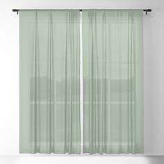 a green curtain hanging on the side of a window in an empty room with white walls