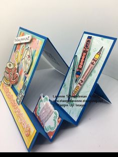 an open card box with some pens and scissors in it on top of a table