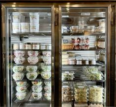 a display case filled with lots of food in front of a glass door freezer