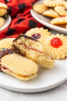 two white plates topped with cookies covered in frosting and sprinkles next to each other