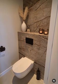 a white toilet sitting inside of a bathroom next to a wall mounted shelf with candles