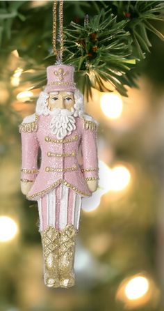 a pink and white ornament hanging from a christmas tree