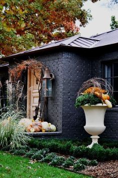 a black house with pumpkins and gourds in the front yard