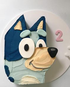 a birthday cake shaped like a dog with eyes and nose on top of a white plate