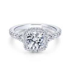 a diamond engagement ring with two halos on the shoulders and an oval center surrounded by round