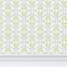 an ornate wallpaper pattern with green and blue accents in a white frame on the wall