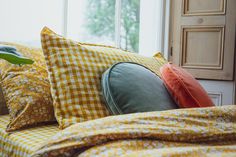 a bed topped with lots of pillows next to a window