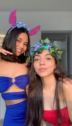 two young women in swimsuits posing for a photo with flowers on their head