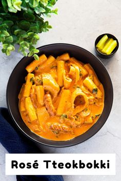 a black bowl filled with pasta and sauce