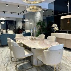 a dining room table with white chairs and a chandelier hanging from the ceiling