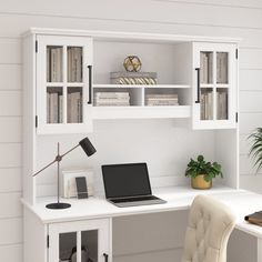 a laptop computer sitting on top of a desk next to a white bookcase and chair