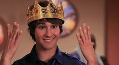 a young man wearing a crown and waving his hands in front of him with both hands up