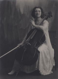 an old photo of a woman holding a cello