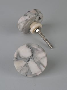 a pair of marbled knobs on a gray surface with a screw in the middle