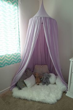 a bed with a canopy and stuffed animals on it in a room next to a window